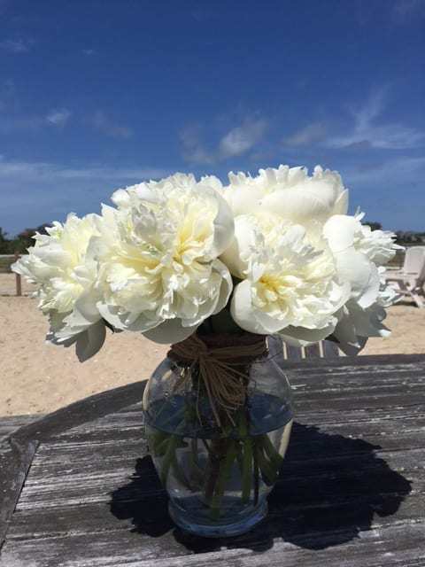 White peony bouquet in a clear glass vase on a table
