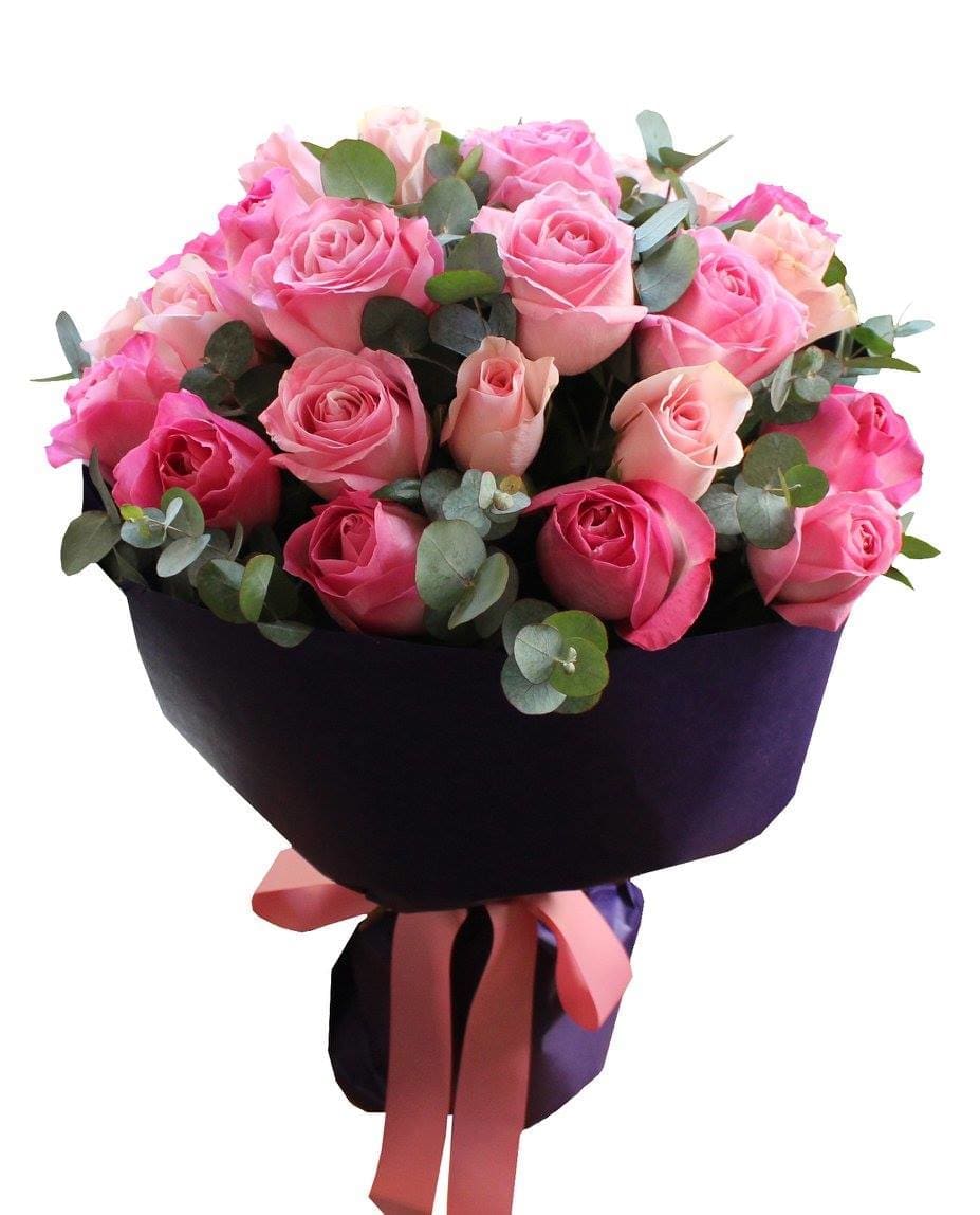 Bouquet of pink roses wrapped in dark paper with a ribbon