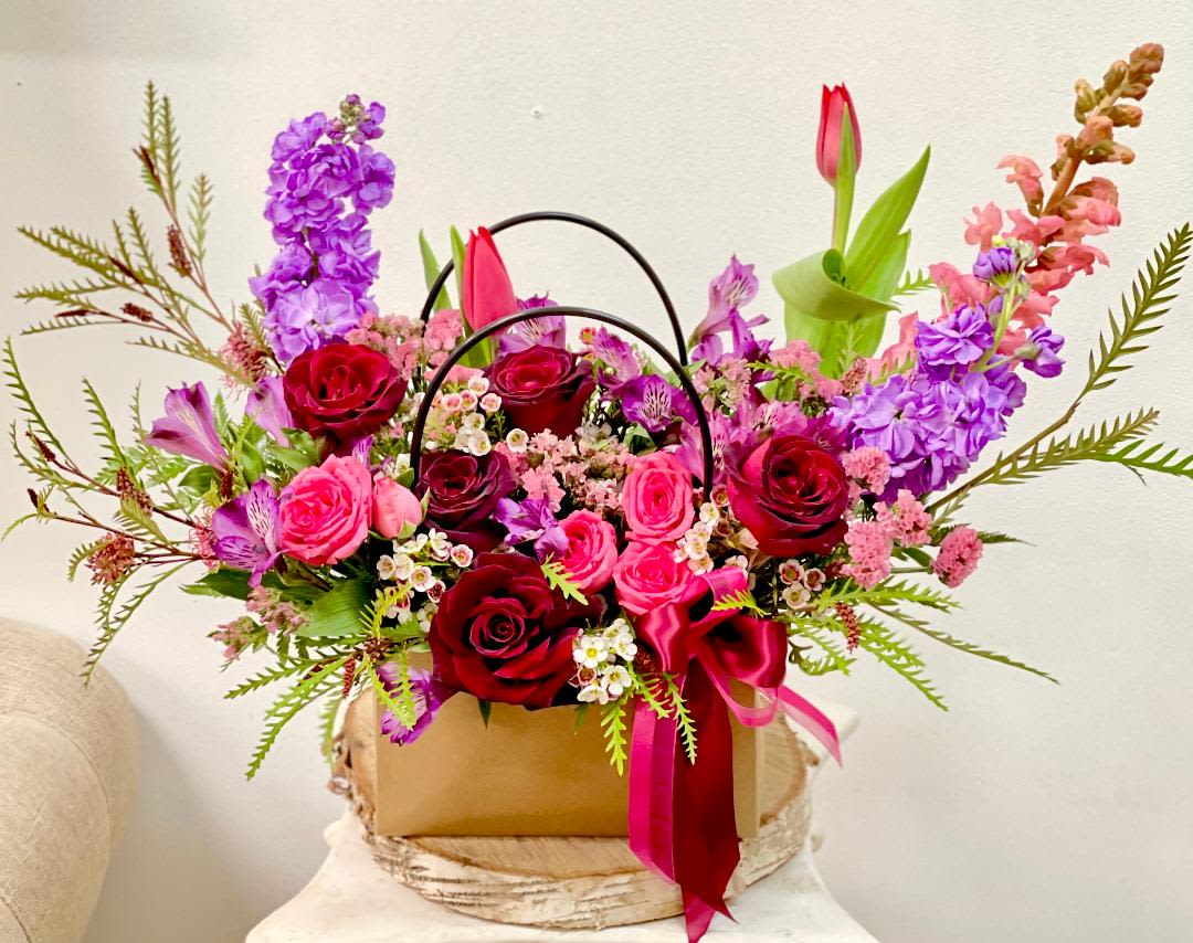 Mixed bouquet of red and pink roses with purple flowers in a gift box