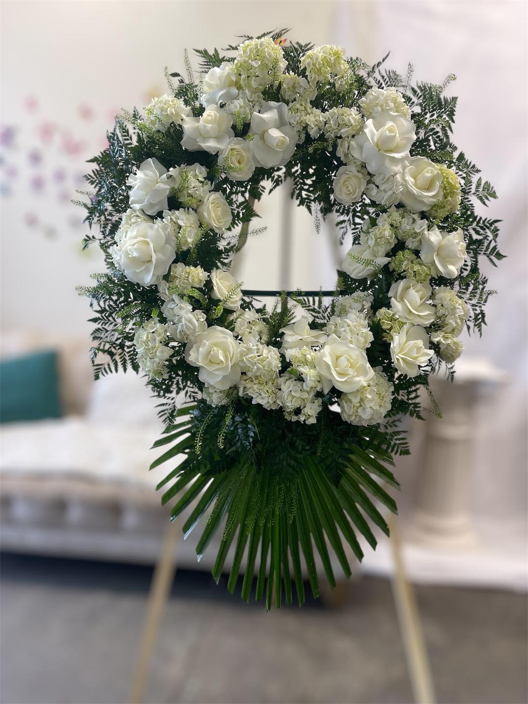 White rose and hydrangea funeral wreath on an easel