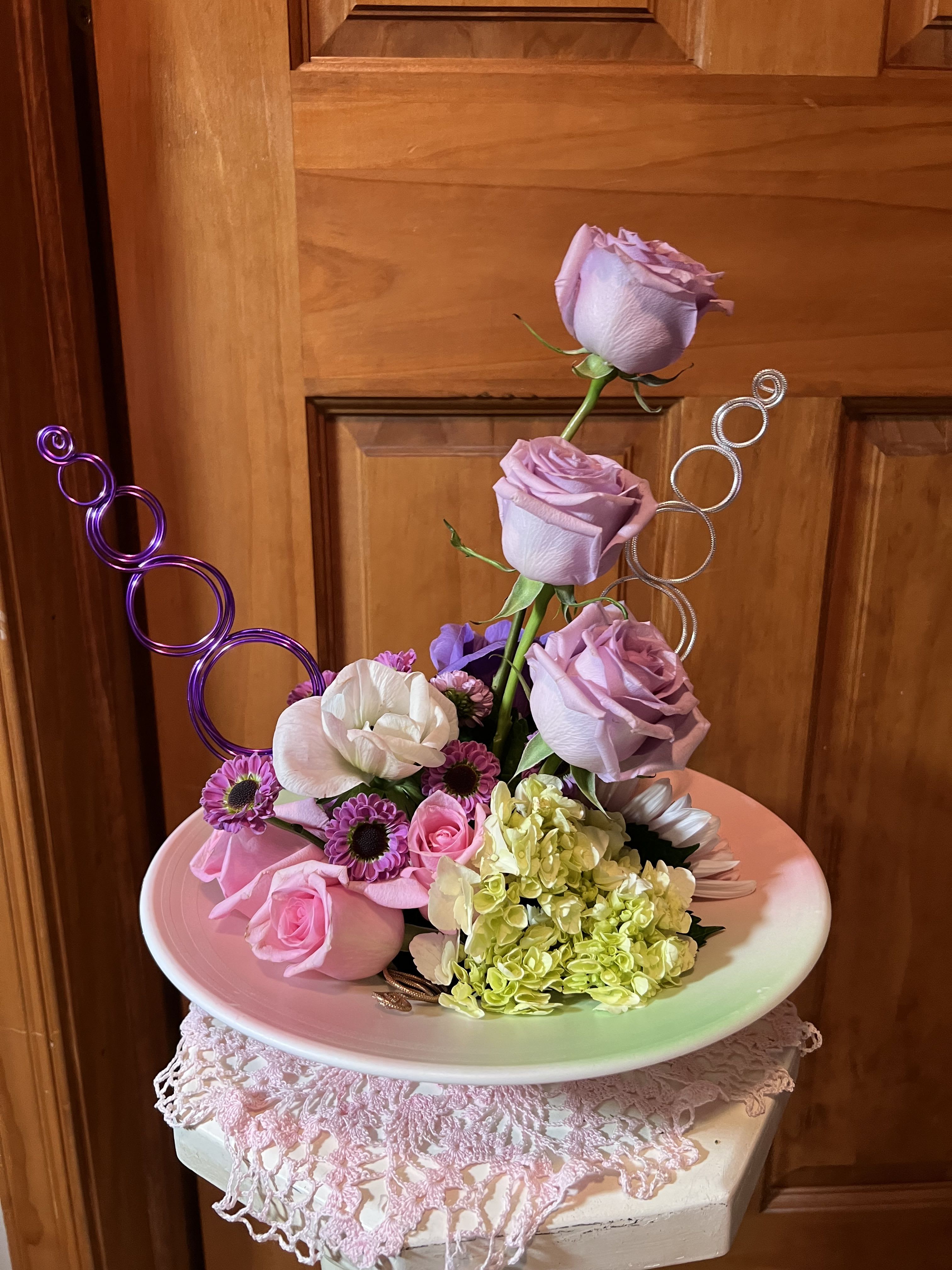 Modern Romance  - This eye-catching arrangement offers a modern twist on the classic 1/2 dozen light pastel colored Roses. Paired with a gorgeous single stem of white Hydrangea, a few tulips and green button chrysanthemums makes a great gift for Valentine's Day, a birthday, or just to let someone know you're thinking of them. Accented with Oasis wire in our choice of shades, nestled in a 11" moss wok shape bowl. 