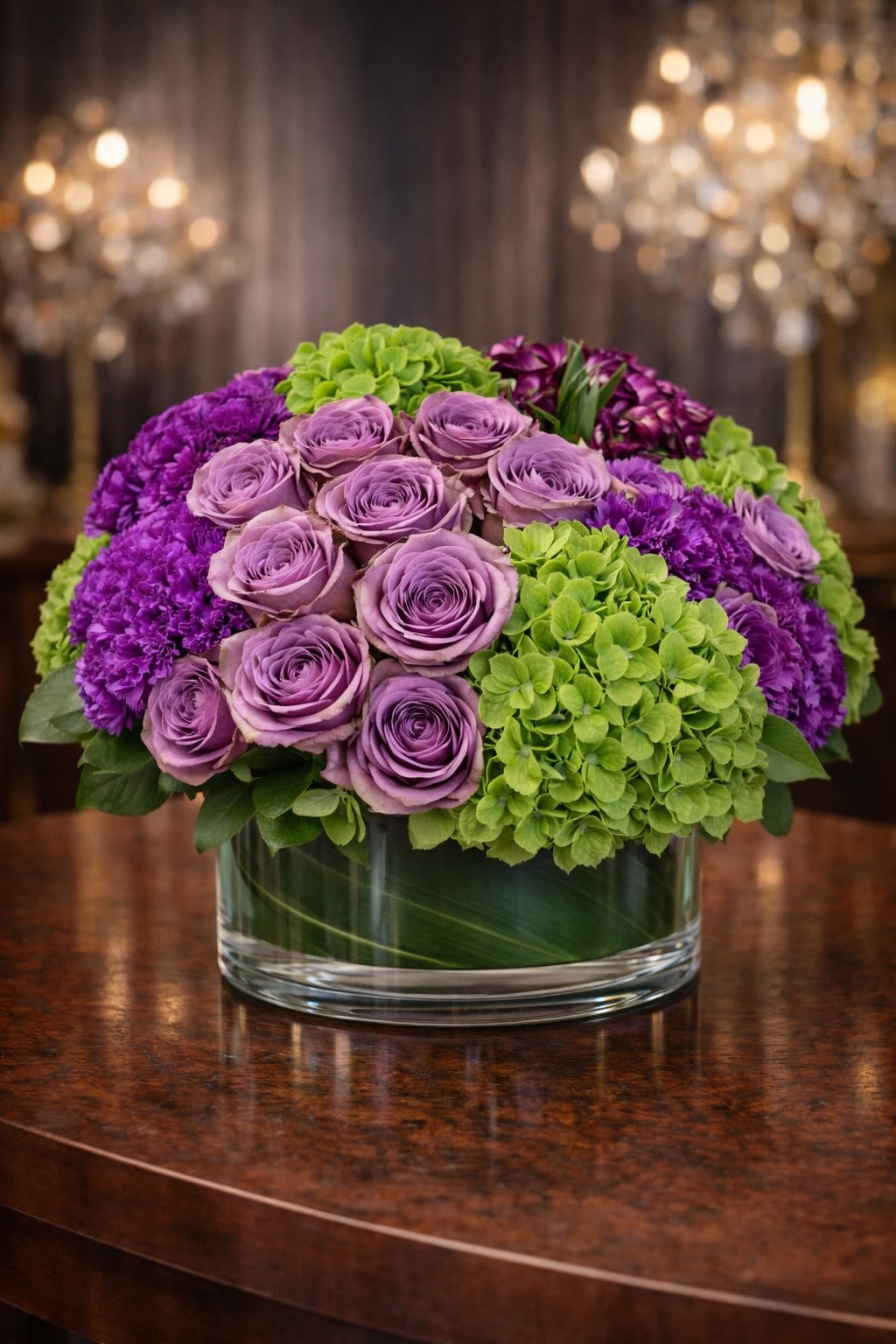 Amethyst Elegance - A rich and sophisticated arrangement featuring premium lavender roses, lush green hydrangea, and textured purple accent blooms arranged in a modern glass cylinder vase. Designed in a balanced, rounded style, this piece blends soft amethyst tones with vibrant green for a refined and contemporary look. The layered textures create depth and fullness, making it a stunning centerpiece or meaningful gift. Perfect for birthdays, anniversaries, congratulations, sympathy gestures, or elegant home décor. • Premium lavender roses • Fresh green hydrangea • Textured purple accent blooms • Seasonal greenery • Modern glass cylinder vase included Handcrafted for fullness, symmetry, and visual impact. ⸻  Seasonal &amp; Freshness Guarantee We select the freshest seasonal blooms available to ensure vibrant color and long-lasting beauty. Because flowers are seasonal and availability may vary, certain accent blooms or greenery may occasionally be substituted. If substitutions are necessary, we will: • Maintain the same purple and green color palette • Preserve the same full, rounded luxury style • Keep the same overall size and premium value • Use flowers of equal or greater quality Your arrangement will always reflect the same elegant aesthetic and color harmony shown — never a different theme or reduced design. Each piece is carefully designed to maintain density, balance, and upscale presentation.
