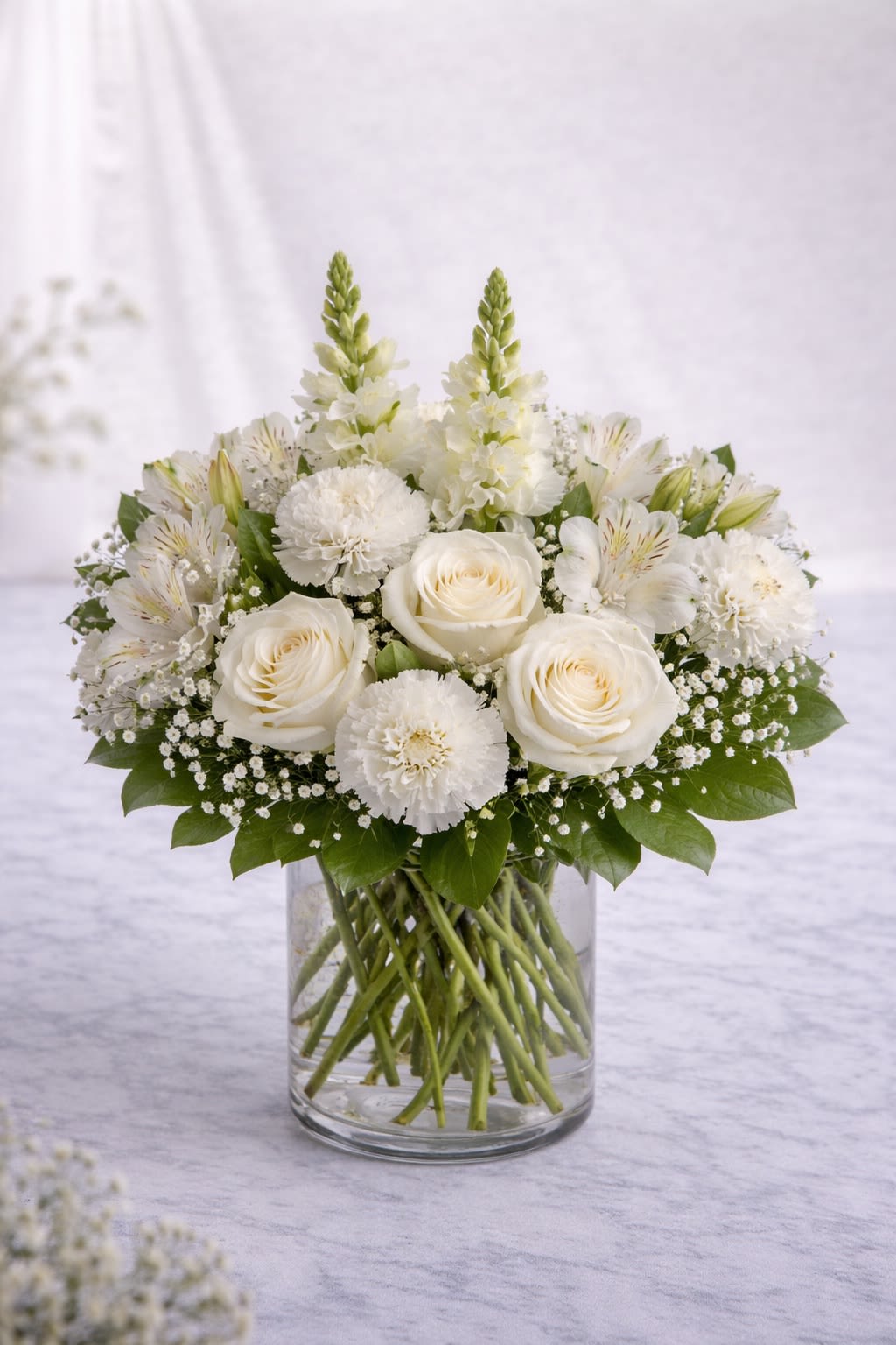 Blushing Meadow - Blushing Meadow is a romantic mix of soft blush roses, creamy ivory blooms, and delicate pastel accents, thoughtfully arranged in a clear glass vase. This design blends roses, carnations, alstroemeria, and airy filler flowers with fresh greenery to create a full, rounded garden-style look that feels elegant yet natural. Perfect for birthdays, anniversaries, sympathy, or simply brightening someone’s day, this arrangement offers a timeless soft color palette that works beautifully for any occasion. Please note: Flower varieties may vary due to seasonal availability. If substitutions are needed, we will always use flowers of equal or higher value while preserving the same color tones and overall style. The container may vary slightly in design, but it will always complement the arrangement’s colors. The look and color harmony will remain true to the photo shown. 