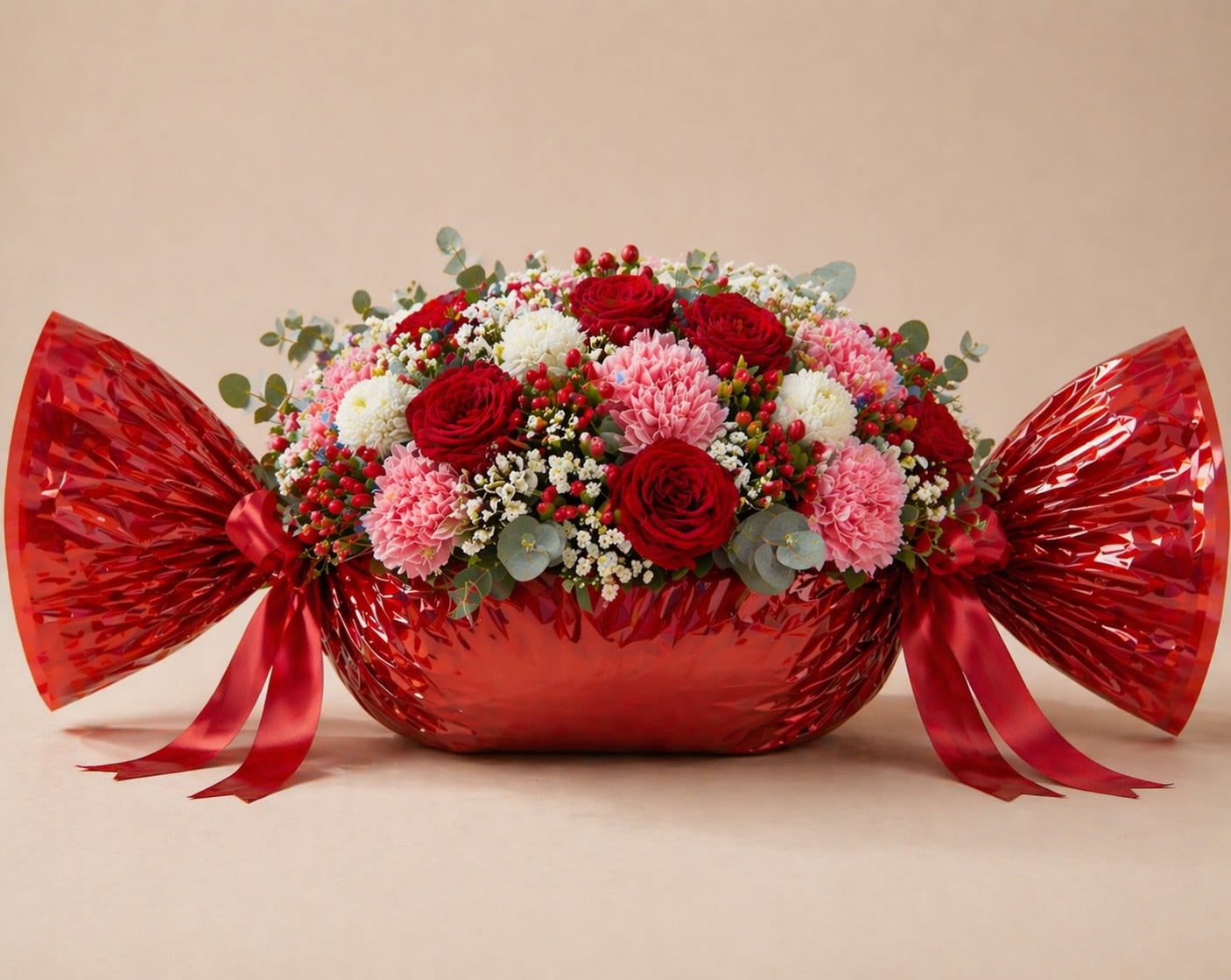 Candy Crush - A playful yet luxurious floral arrangement designed to look like a giant wrapped candy. Candy Crush features premium red roses, soft pink carnations, fluffy white cushion pom poms, delicate baby’s breath, vibrant hypericum berries, and fresh eucalyptus for a modern, textured finish. Wrapped in glossy red with elegant ribbon ties, this design is bold, romantic, and eye-catching—perfect for Mother’s Day, birthdays, or anyone who loves something unique and fun with a luxury feel. It’s a statement piece that feels both sweet and upscale.