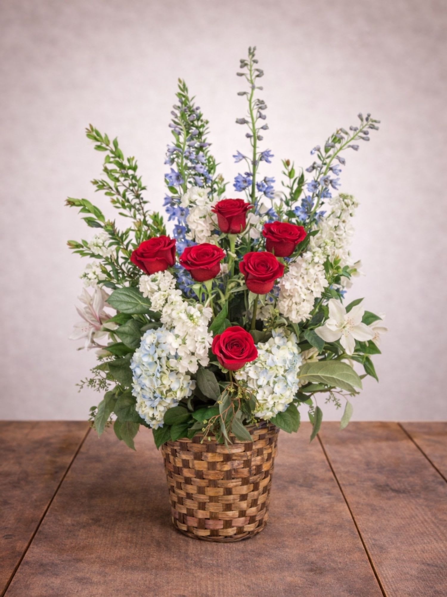 Red roses and blue-white flowers arranged in a woven basket