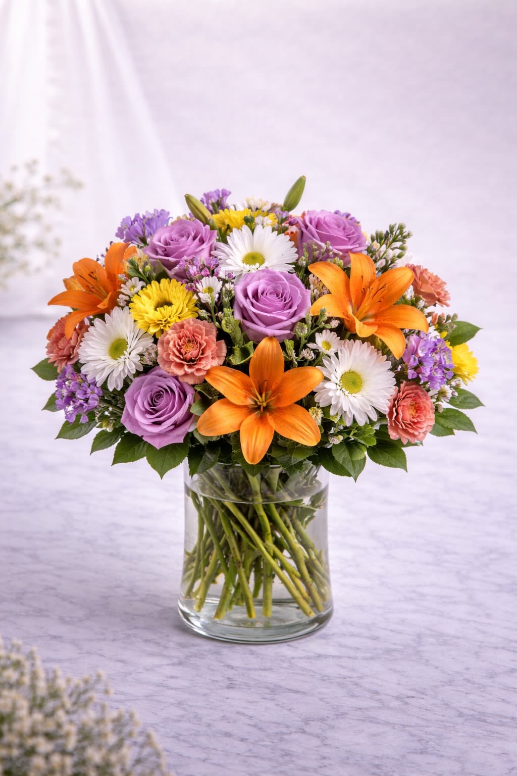 Sunlit Romance Grand - A vibrant and joyful arrangement that blends elegance with bold color. Radiant yellow lilies bloom beautifully among rich red roses, soft pink carnations, and delicate seasonal accents, all nestled in fresh greenery. The contrast of warm golden tones and deep romantic reds creates a design that feels both uplifting and heartfelt. Perfect for anniversaries, celebrations, or sending a message of love and happiness. Substitution Policy: Flower varieties may vary depending on seasonal availability, but the bright yellow and rich red color palette will always remain the same. Any substitutions will be thoughtfully chosen to preserve the overall fullness, balance, and style of the arrangement. Containers will always complement the colors and design to ensure a cohesive, beautiful presentation.