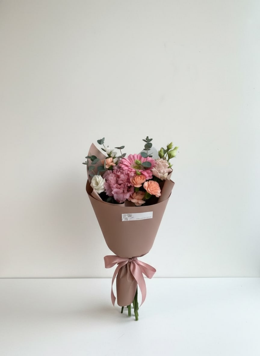 Bloom Bouquet - Hand-Tied Designer’s Choice Bouquet Our Hand-Tied Designer’s Choice Bouquet features a seasonal mix of fresh blooms thoughtfully selected by our floral designers. Each bouquet is artfully arranged, wrapped in premium floral paper, and finished with a satin ribbon for a polished, gift-ready presentation. Perfect for celebrations, heartfelt moments, or just because—no two bouquets are exactly alike, making each one uniquely special.  Florist’s choice blooms. Color palette and flowers may vary based on seasonal availability.