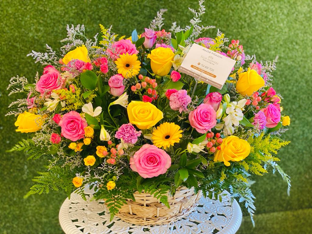 Basket arrangement of pink and yellow roses with mixed flowers