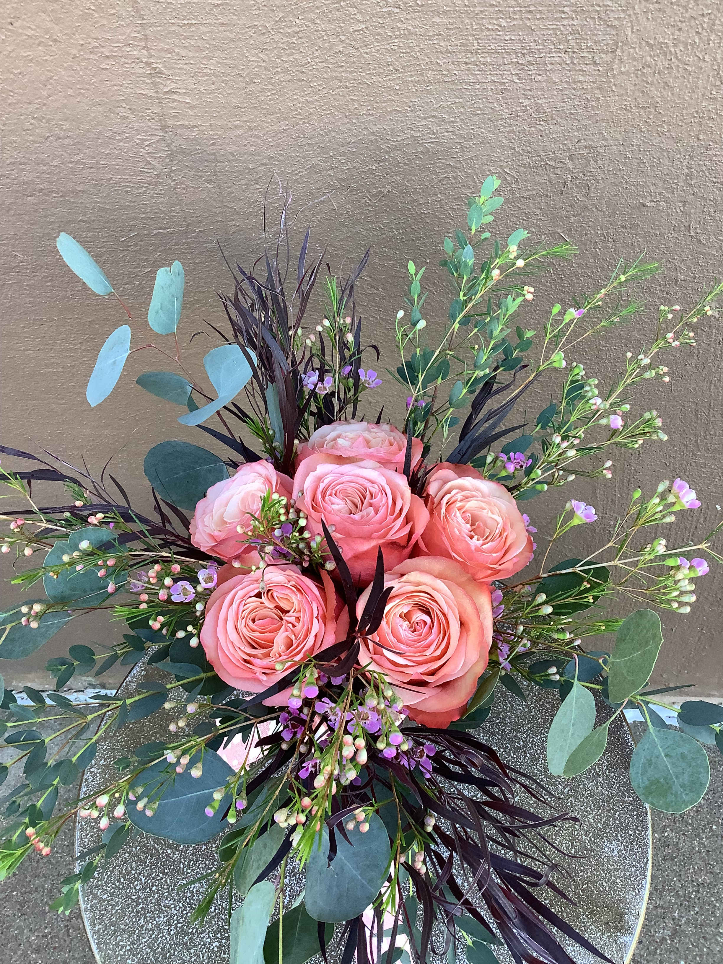 Pink roses arranged with eucalyptus and purple filler flowers
