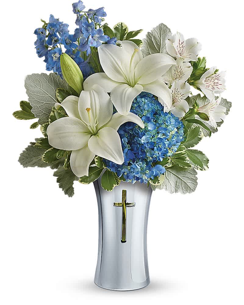 White lilies and blue flowers in a silver vase with a cross