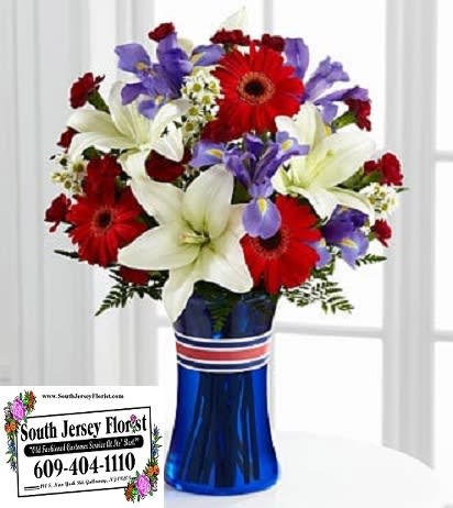 Bouquet of red gerbera daisies, white lilies, and purple irises in a blue vase