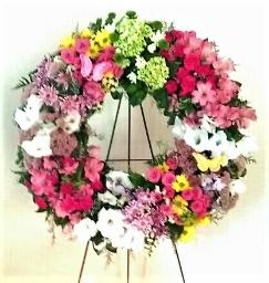 Colorful floral wreath on a stand with pink, white, yellow, and green blooms