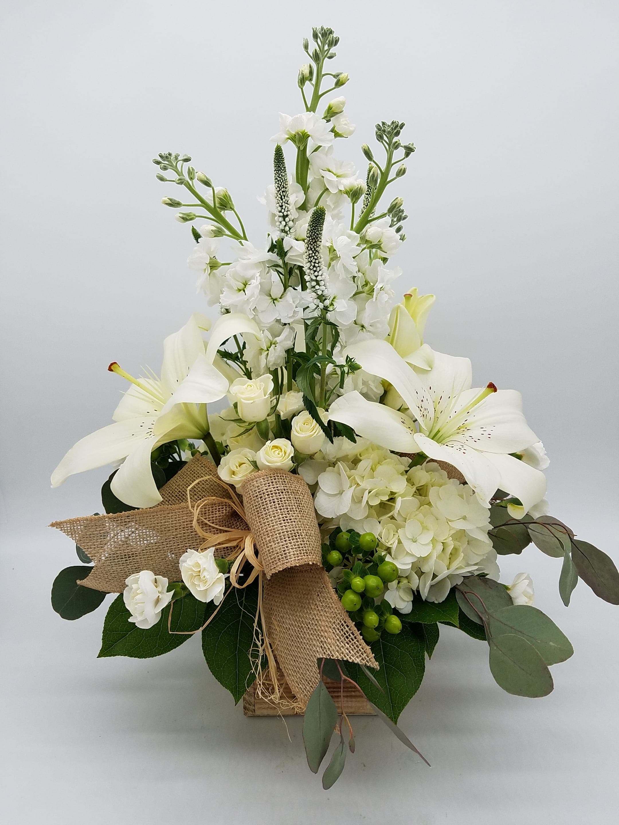 White lilies and roses arranged in a burlap-wrapped box