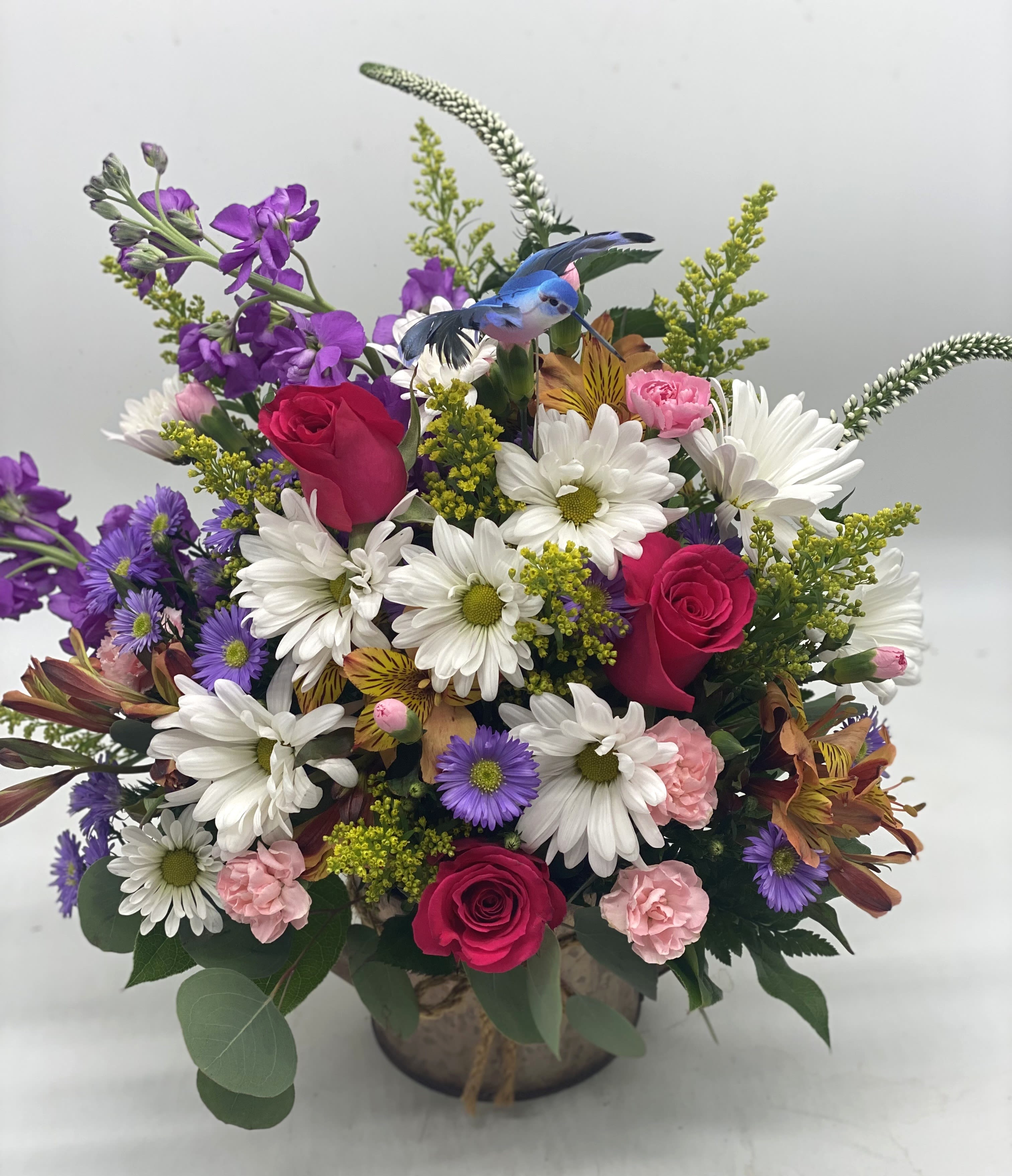 Mixed bouquet of roses, daisies, and purple flowers in a vase