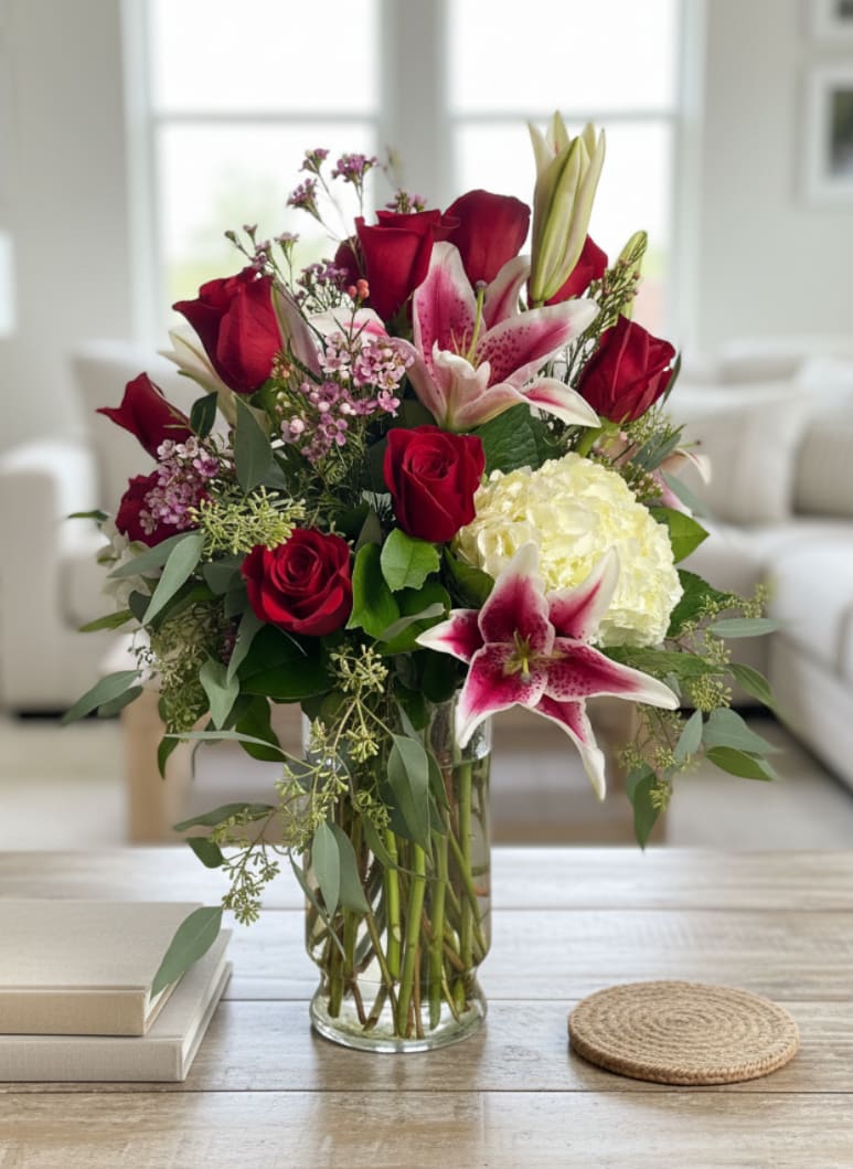 Red roses and pink lilies arranged in a clear glass vase
