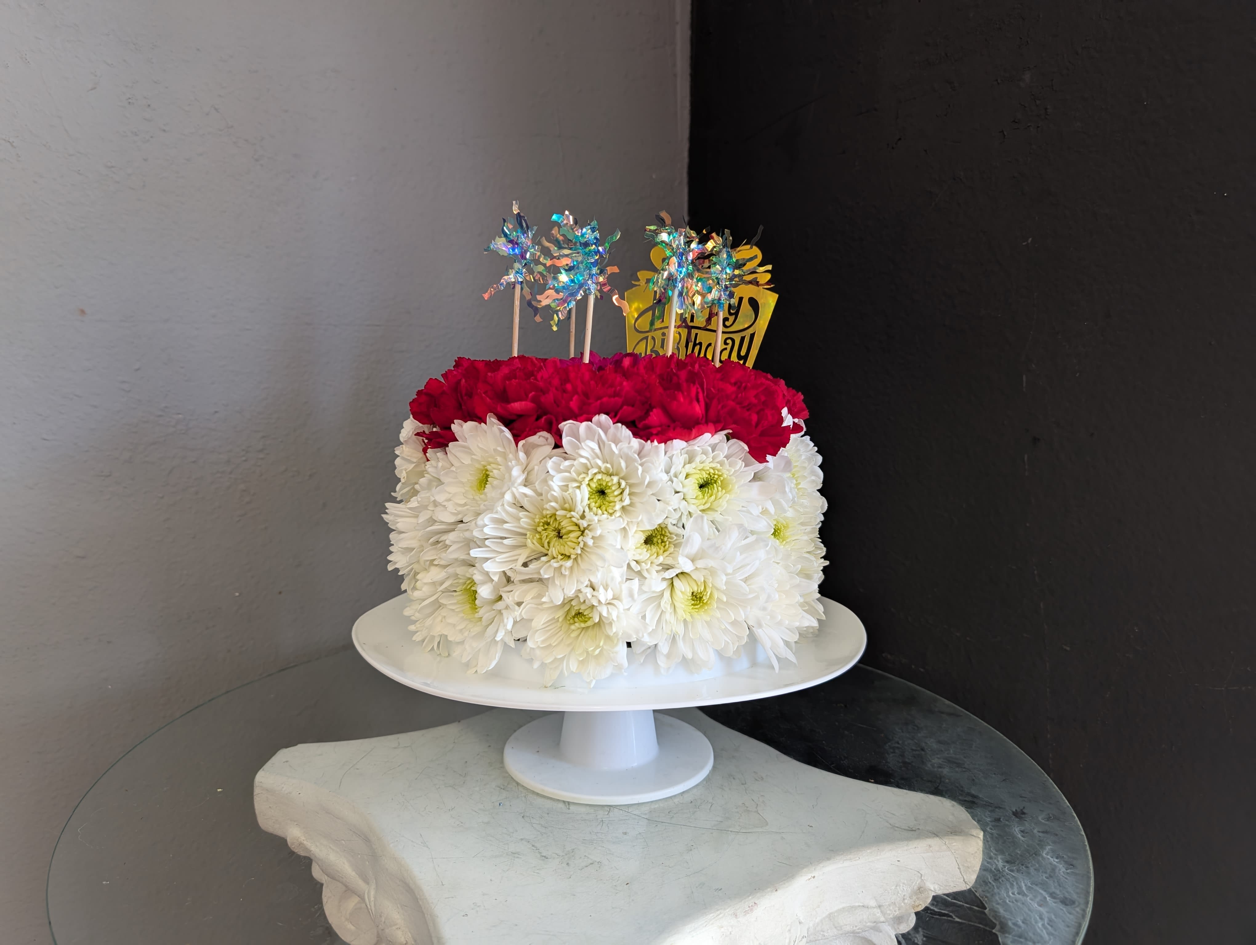 Blooming Birthday Cake - This adorable cake arrangement is sure to put a smile on any lucky recipient. It features carnations, daisies, roses and spray roses! Flower type and color WILL vary and be based on available stock at the time of order. If you have any special requests, please call us at 714-289-1123.