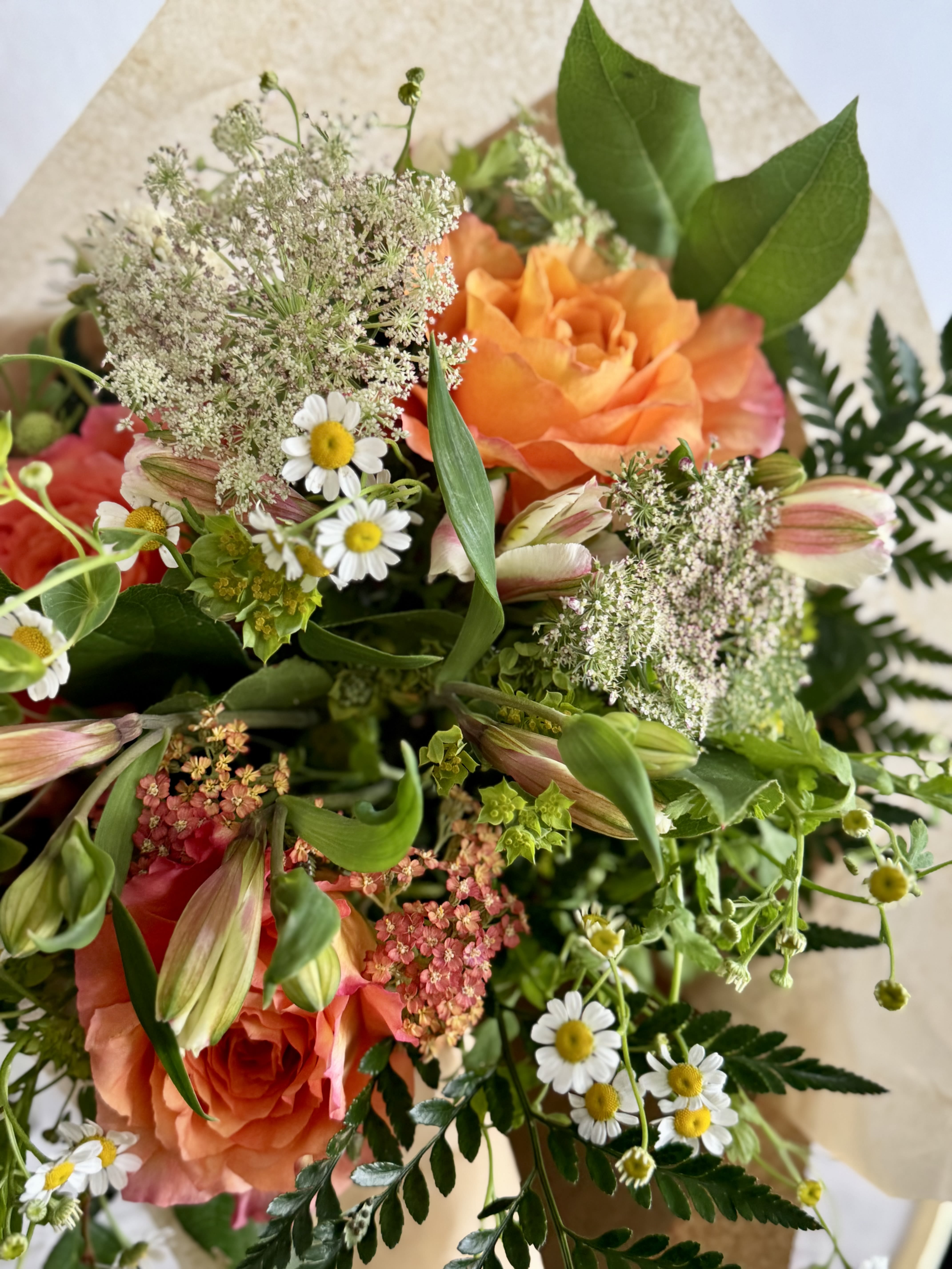 Wild cutie PETITE hand tied  - A burst of orange and soft pink-and-cream creates an instantly cheerful, hand-tied birthday or thank-you bouquet that feels like a pocket-sized garden. This petite flower arrangement for everyday gifting is a gardens style wild  hand tied  bouquet the is loose and textural all wrapped in simple brown paper for a natural, gift-ready look.  Sized to be compact and easy to carry, it's ideal for spring occasions, a small anniversary surprise, or a thoughtful just-because moment; keep stems trimmed and fresh water available to extend bloom life.