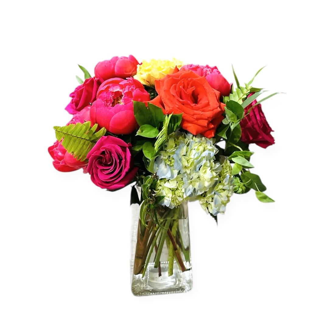 Bright mixed bouquet of pink and orange roses, peonies, and hydrangeas in a clear glass vase