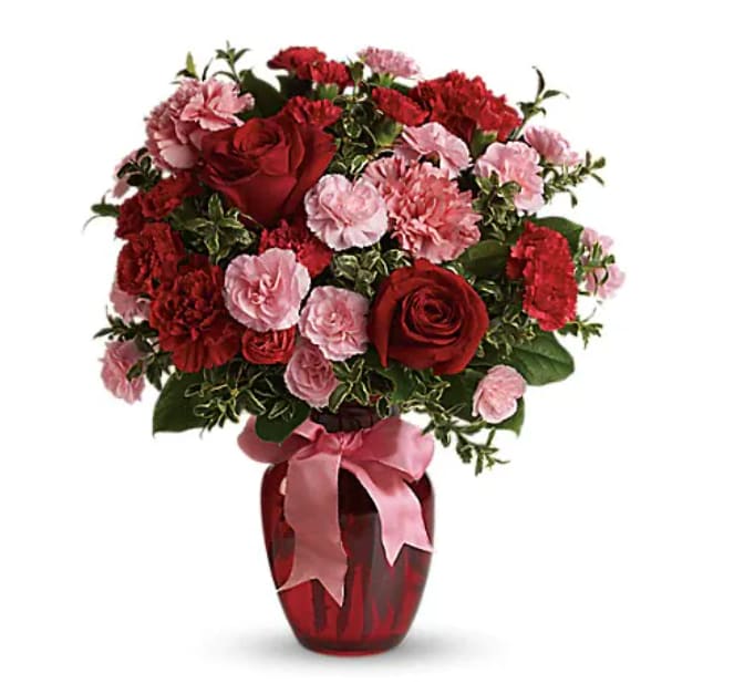 Red roses and pink carnations in a red vase with a pink ribbon