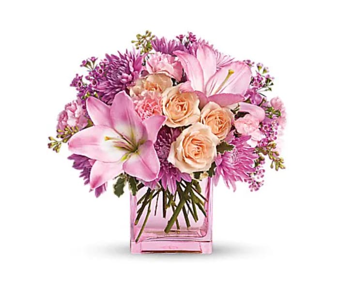 Pink and peach bouquet in a square glass vase