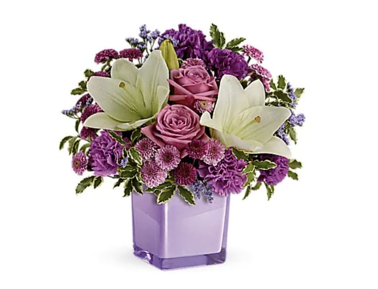 Purple and pink bouquet with white lilies in a lavender vase