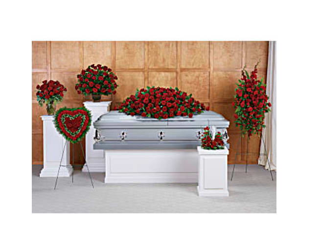 Funeral casket surrounded by red rose sprays and wreaths