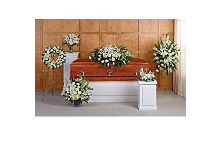 Funeral casket surrounded by white floral sprays and wreaths