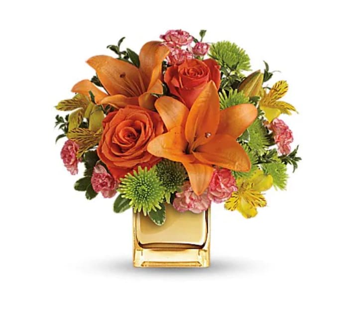 Tropical Punch Bouquet - Glow for it! Capture the magic of a tropical sunset with this gorgeously glowing bouquet. Lush lilies and roses in radiant shades of orange and yellow are presented in a golden Mirrored Cube for a touch of instant glam. Soft orange roses, asiatic lilies and miniature carnations are arranged with yellow alstroemeria and green button spray chrysanthemums. Delicate oregonia and pittosporum add contrast. Delivered in a Mirrored Cube. 