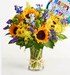 Father's Day Blooms - This bright beautiful bouquet is surely going put a smile on your dad's face for Father's Day. With sunflowers, blue delphaninum, green mums, purple statice, daisies, mini Father's Day mylar, and much more.