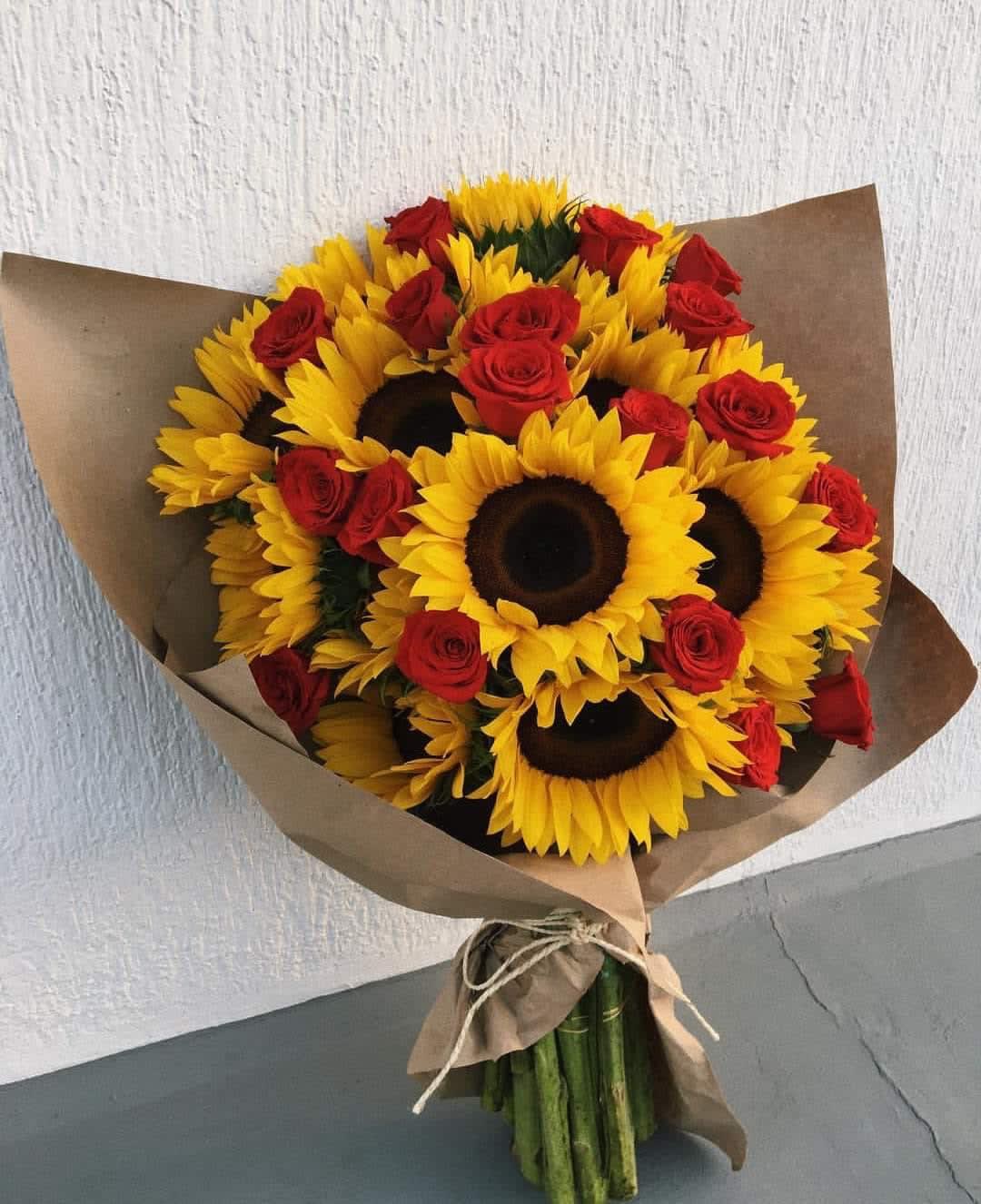 Bouquet of sunflowers and red roses wrapped in brown paper
