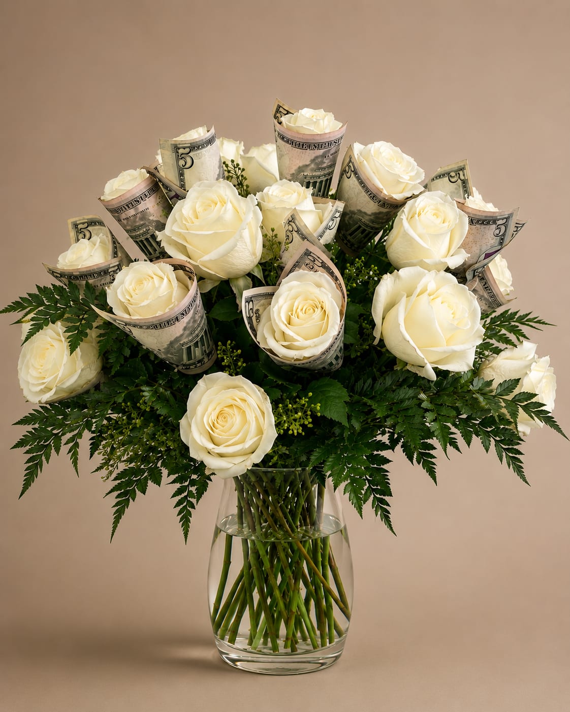 Ivory cash rose bouquet - Cream-white roses clustered into a classic rounded bouquet create an elegant, celebratory look-perfect as a congratulations arrangement or special celebration gift. The cream-white rose bouquet in a clear glass vase is designed to make the recipient feel honored and spoiled, the kind of floral gift that announces a milestone or achievement with quiet luxury.  The arrangement pairs tightly bunched ivory roses with deep green foliage for strong contrast and a lush, full silhouette. Folded paper currency is artfully tucked among the blooms, giving the design a playful, gift-like touch while keeping the focus on the soft, creamy petals. Displayed in a clear glass vase, the bouquet measures as a compact, table-ready centerpiece that complements both modern and classic décor.  A thoughtful choice for graduations, promotions, milestone birthdays, or any moment you want to celebrate with style-she'll feel genuinely seen and celebrated when this arrangement arrives. Simple care: refresh the water every few days and trim stems as needed to maintain vase life.
