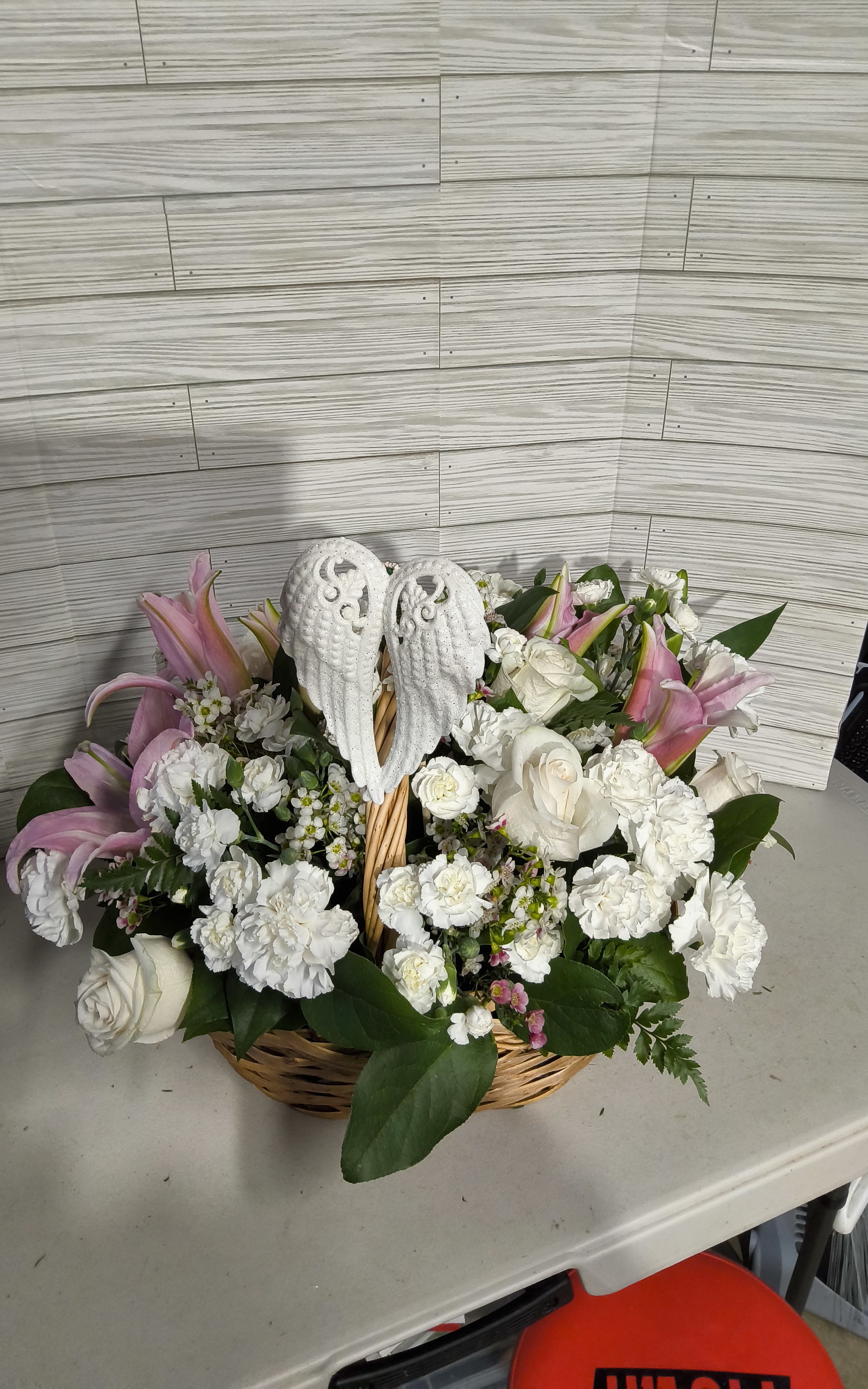 Basket arrangement of white roses, carnations, and pink lilies with angel wings