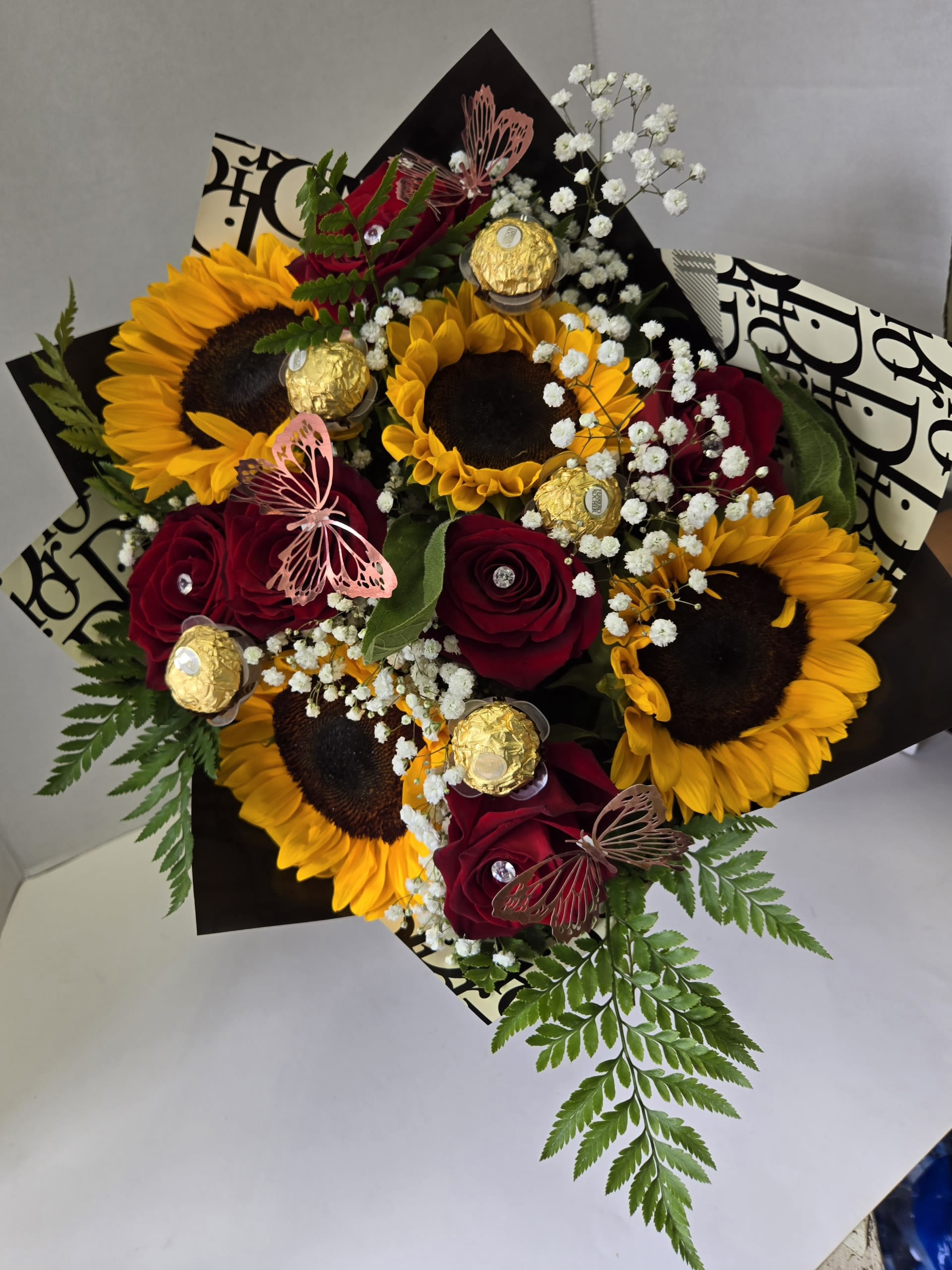 Bouquet of sunflowers and red roses with baby’s breath and chocolates