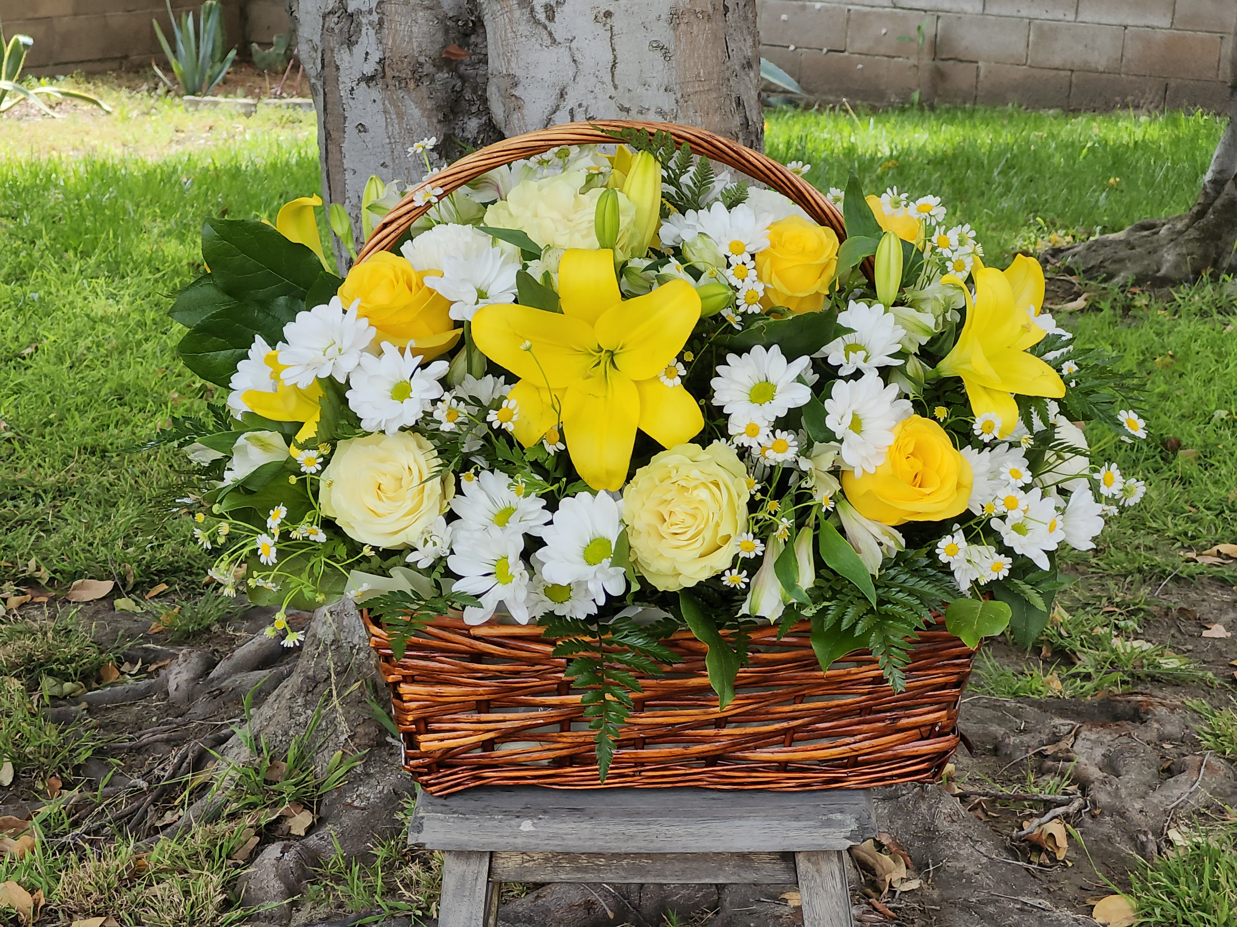 Basket arrangement of yellow lilies, roses, and white daisies