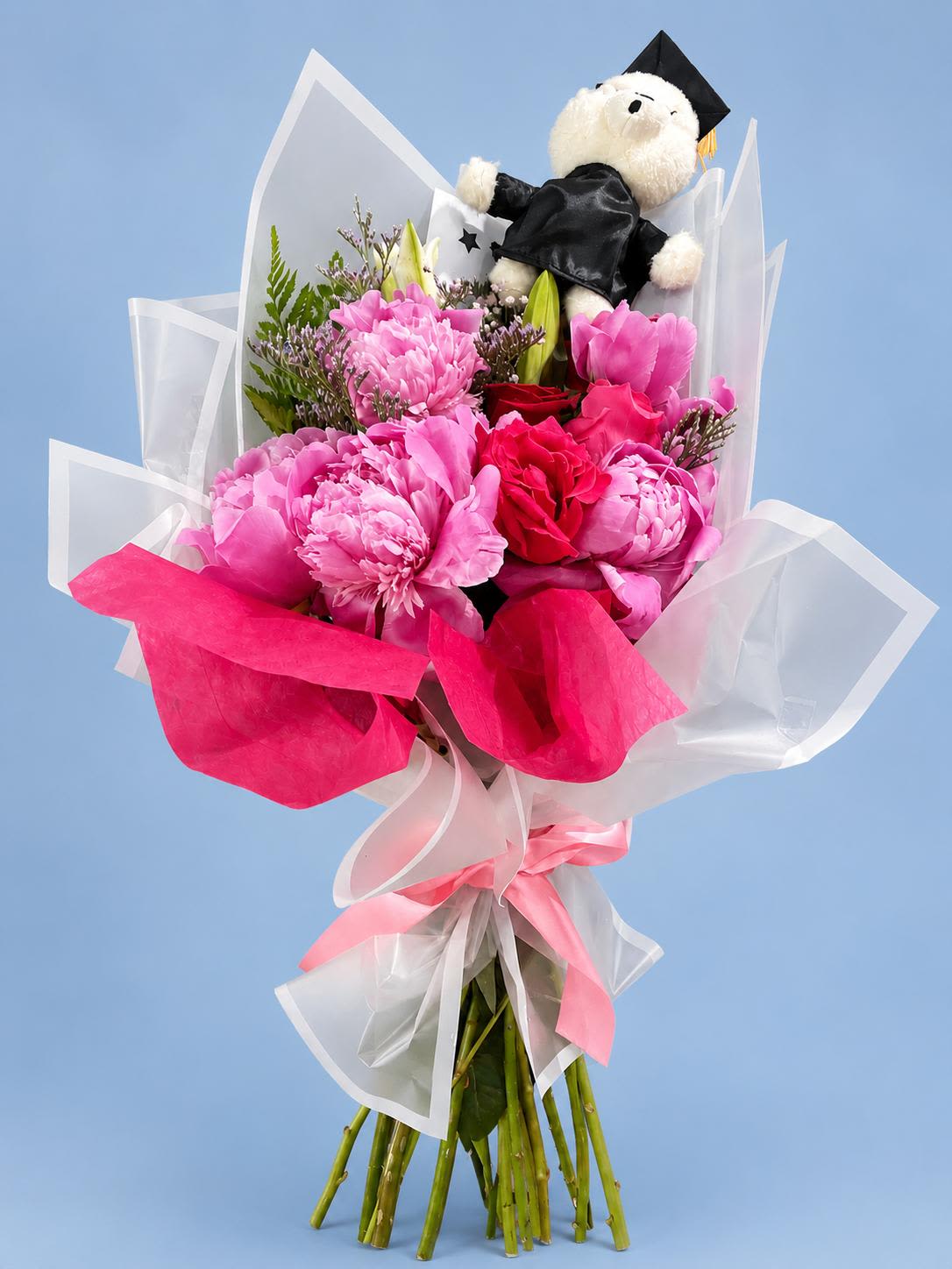 Gaduation Bouquet - Celebrate academic success with this elegant handcrafted graduation bouquet, designed to make any graduation feel extra special. This arrangement features lush pink peonies, vibrant red roses, delicate filler flowers, and fresh greenery beautifully wrapped in premium translucent white and hot pink floral paper 
