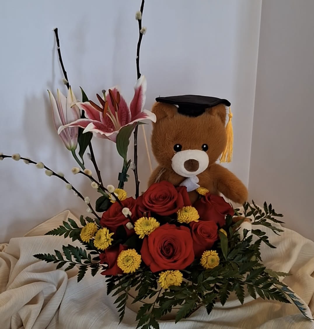 Radiant Scholar Success - A sophisticated graduation masterpiece presented in an embellished black gala box. This premium arrangement blends red and pink roses with striking stargazing lilies and delicate baby's breath. Beautifully detailed with a festive "Congrats Grad" pennant flag, a glittery mini mortarboard cap, and a majestic gold bow featuring a keepsake songbird accent.