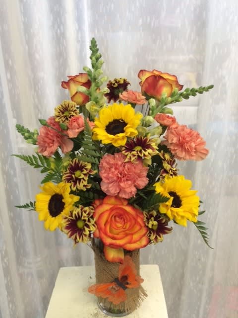 Bouquet of sunflowers, roses, and carnations in a glass vase