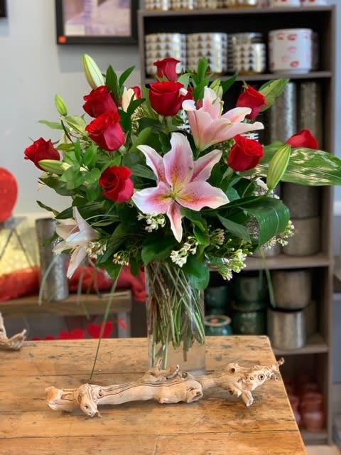 Bouquet of red roses and pink lilies in a clear glass vase