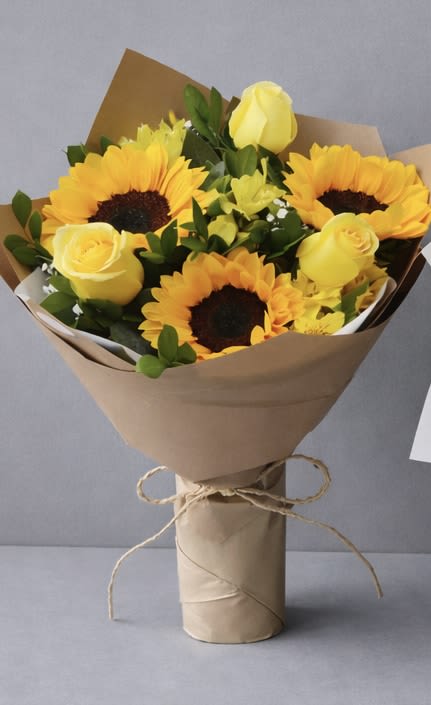Bouquet of yellow sunflowers and roses wrapped in brown paper