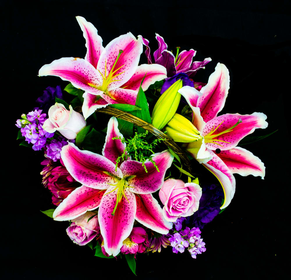 Pink stargazer lilies and roses in a basket arrangement