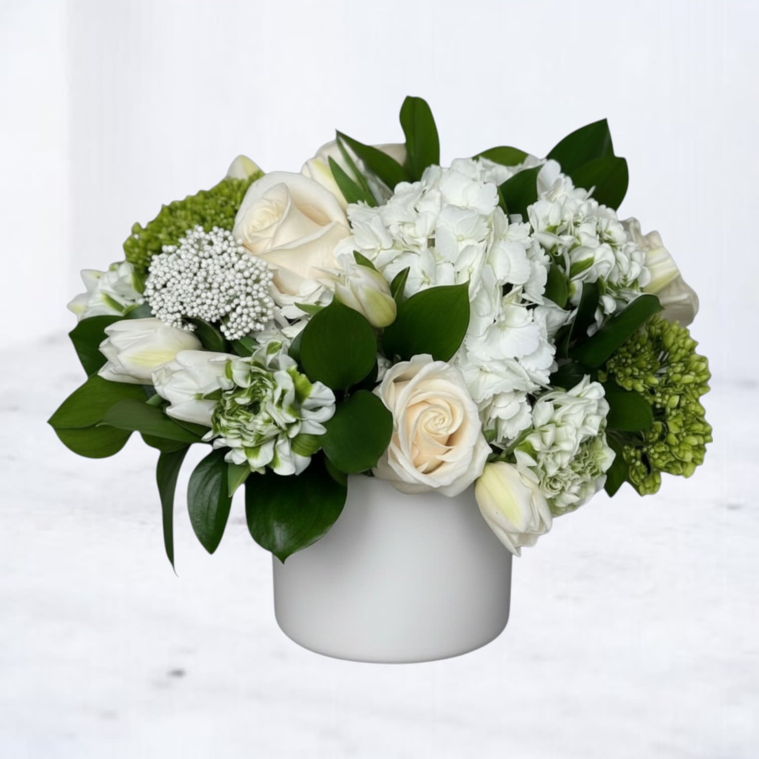 Emerald Oasis - Emerald Oasis is a refined, modern floral arrangement designed with a crisp white and lush green palette for a clean, sophisticated look. Featuring white roses, hydrangea, tulips, and seasonal blooms, this arrangement is layered with rich greenery to create a full, balanced, and naturally elegant composition.  Designed in a matte black vessel, Emerald Oasis blends classic floral elements with a contemporary, design-forward edge. The contrast of soft white blooms against deep green foliage and the bold black container creates a striking, minimalist aesthetic that feels both timeless and elevated.  Perfect for sympathy flowers, funeral services, corporate gifting, thank-you gestures, or sending a calm, thoughtful message, this white and green floral arrangement offers a polished, versatile design suitable for any setting.  Same-day flower delivery is available in Magnolia, TX, The Woodlands, Montgomery, Conroe, Spring, Tomball, and surrounding North Houston areas.  Due to seasonal availability, some blooms may be replaced with similar varieties of equal or greater value to maintain the design’s look and integrity. Your arrangement will always reflect the same color palette, style, and premium quality.
