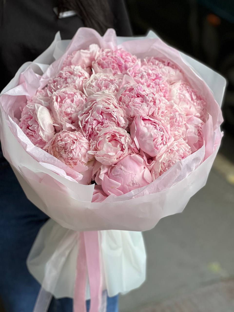 Bouquet of pale pink peonies wrapped in white paper