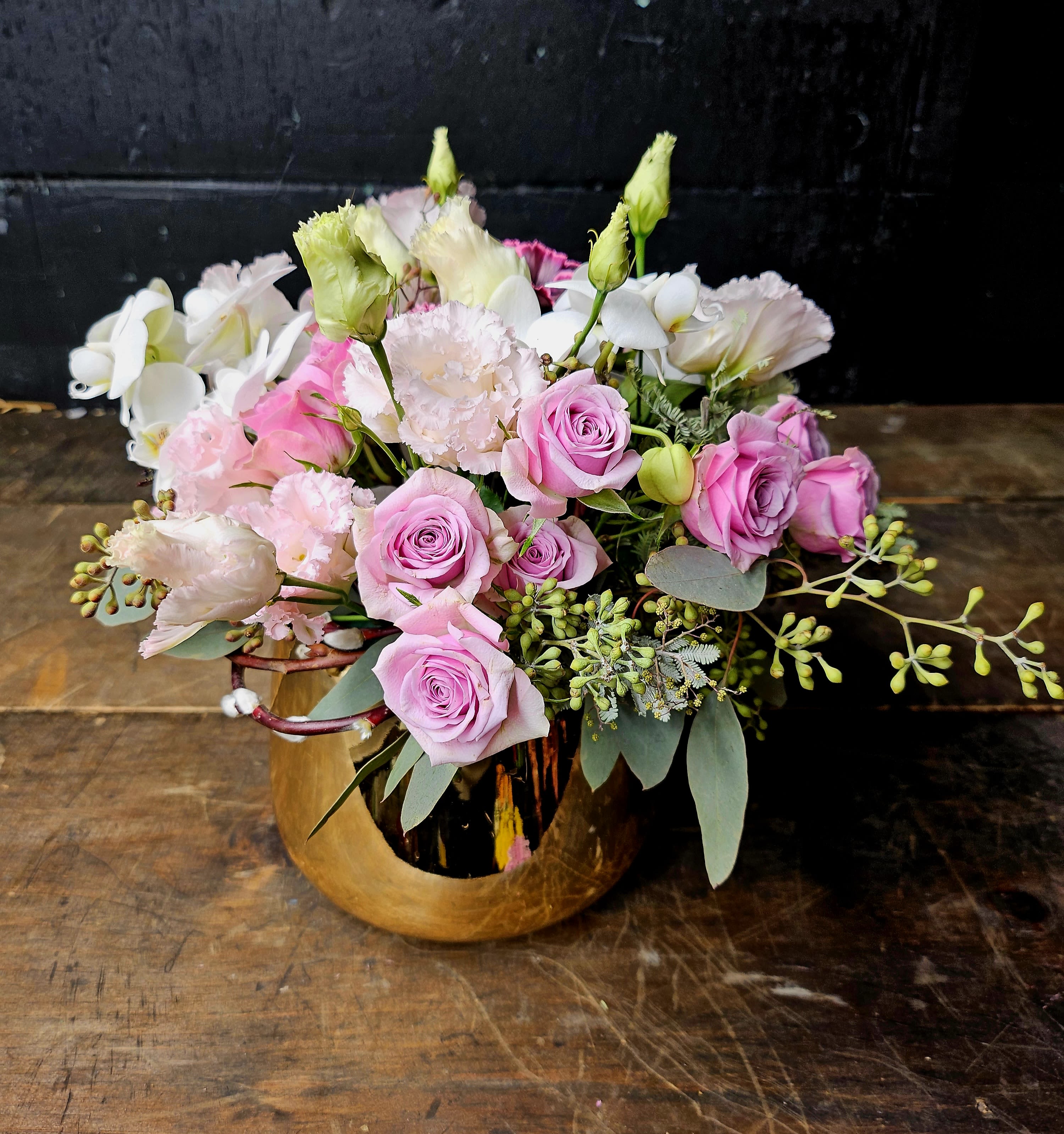 Pink roses and white blooms arranged in a gold vase