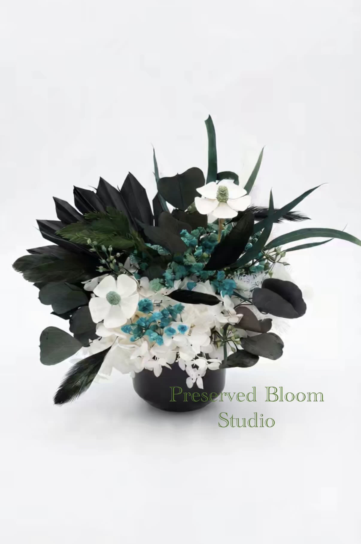 Black and white floral arrangement in a black vase with blue accents