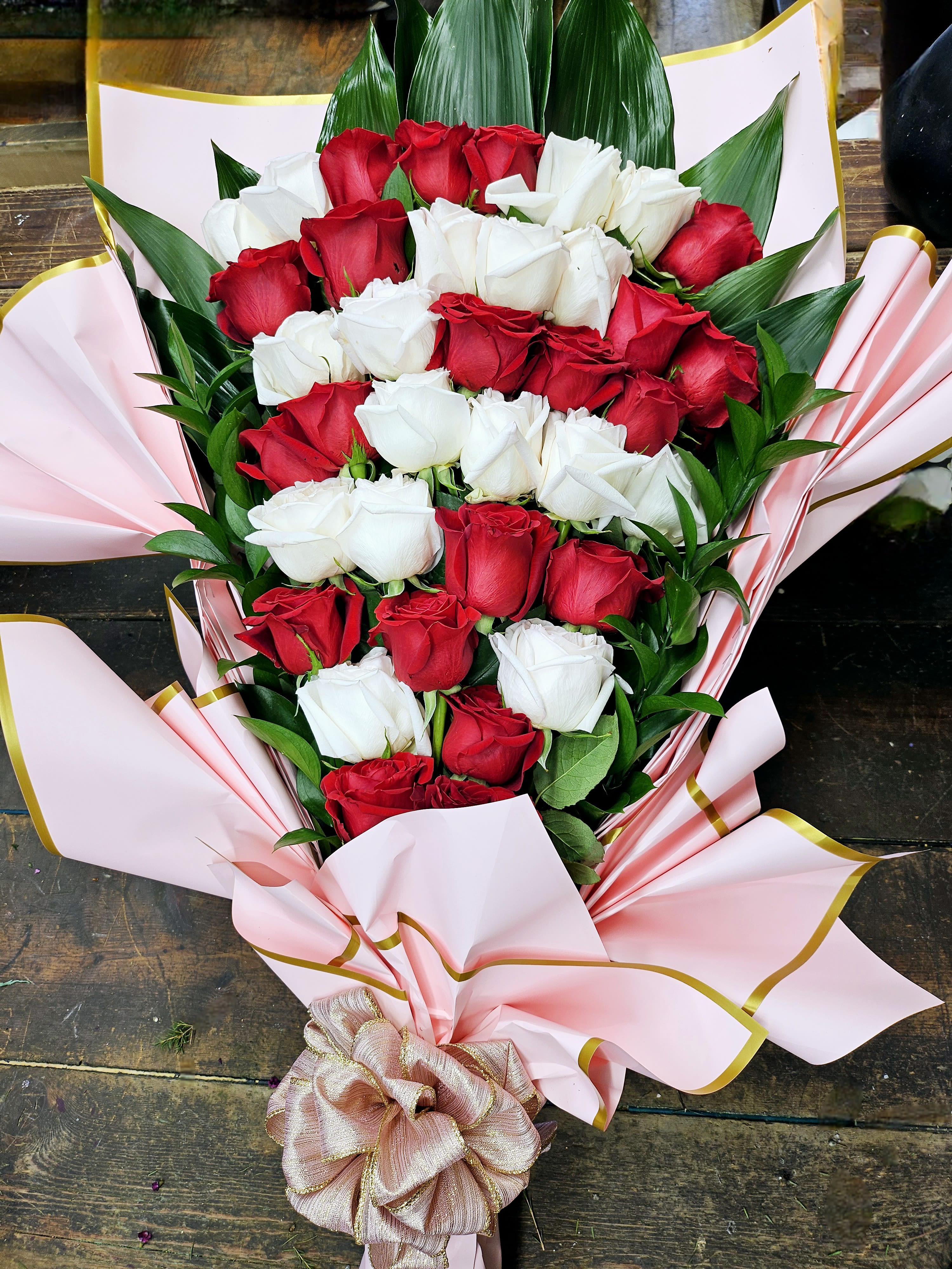 Bouquet of red and white roses wrapped in pink paper