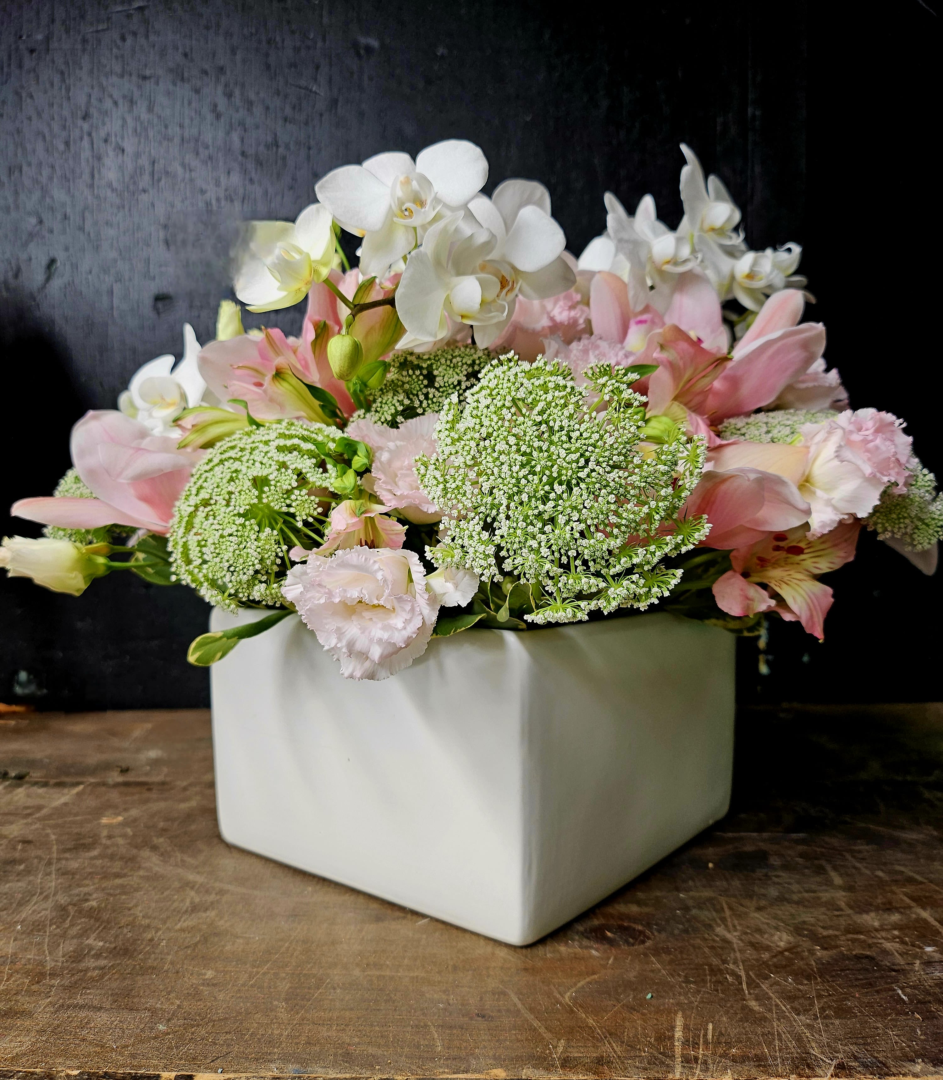 Pink and white floral arrangement in a white square vase