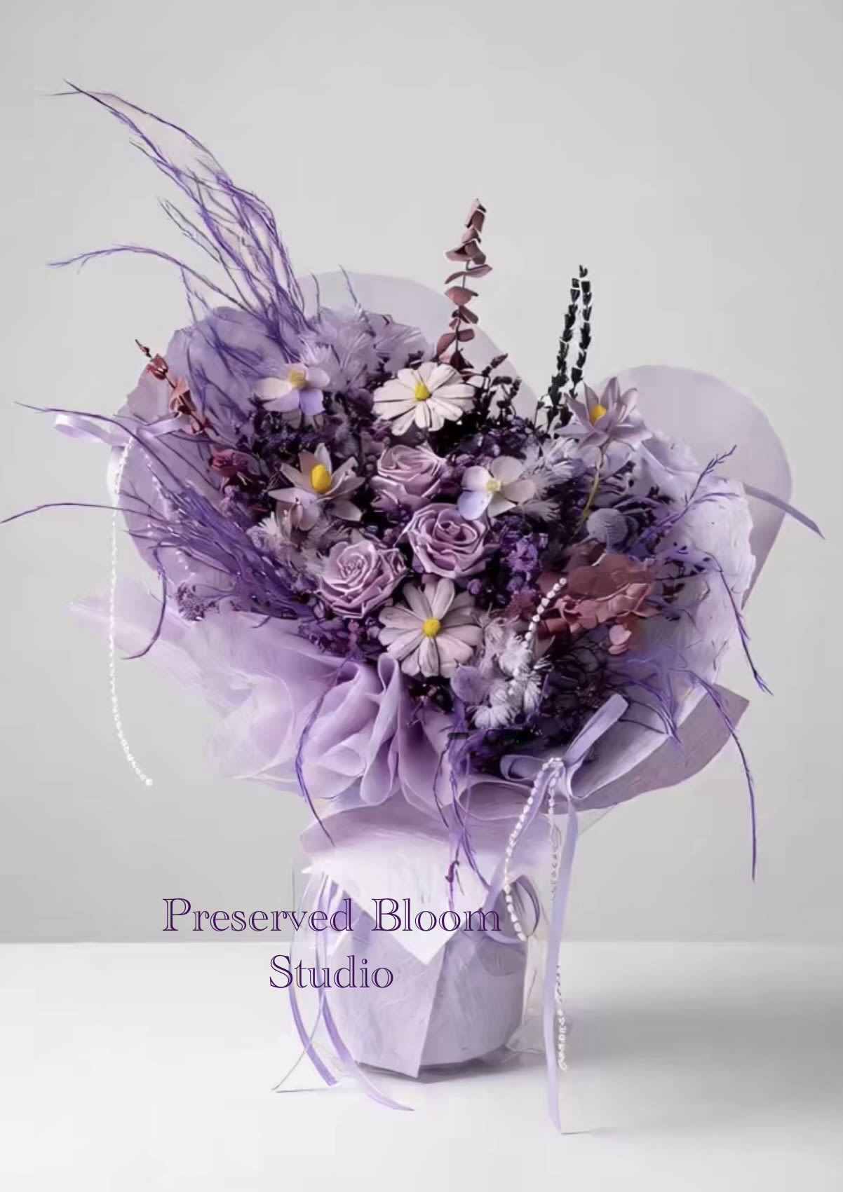 Lavender bouquet with roses and daisy-like flowers wrapped in purple paper