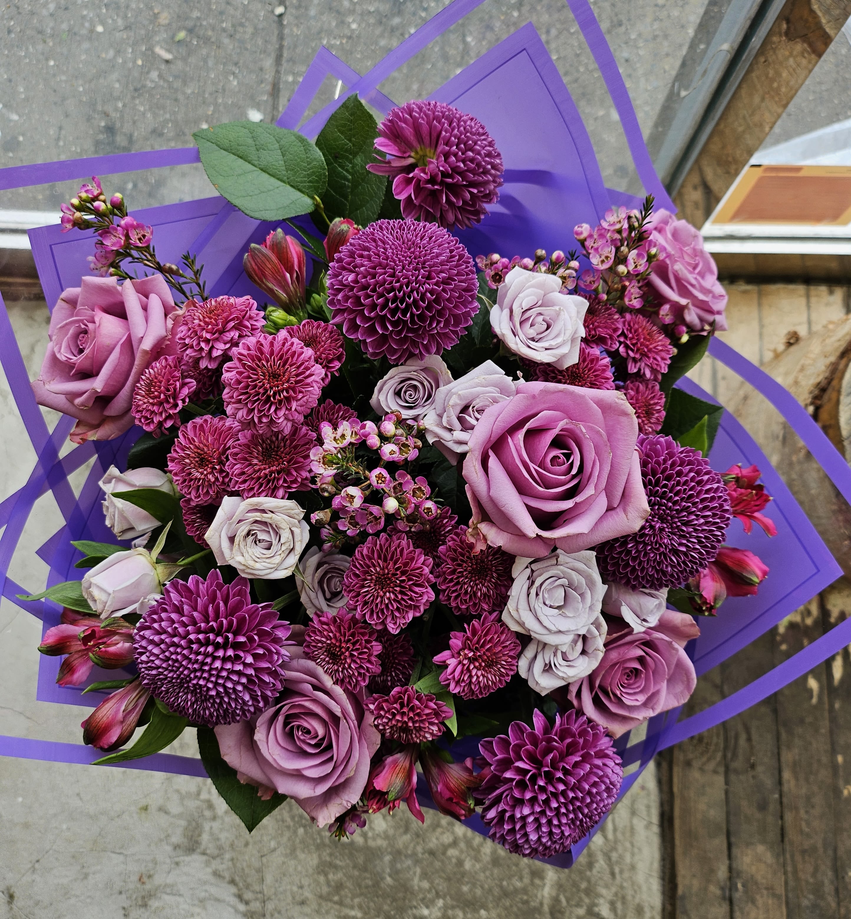 Bouquet of purple roses and magenta chrysanthemums wrapped in purple paper
