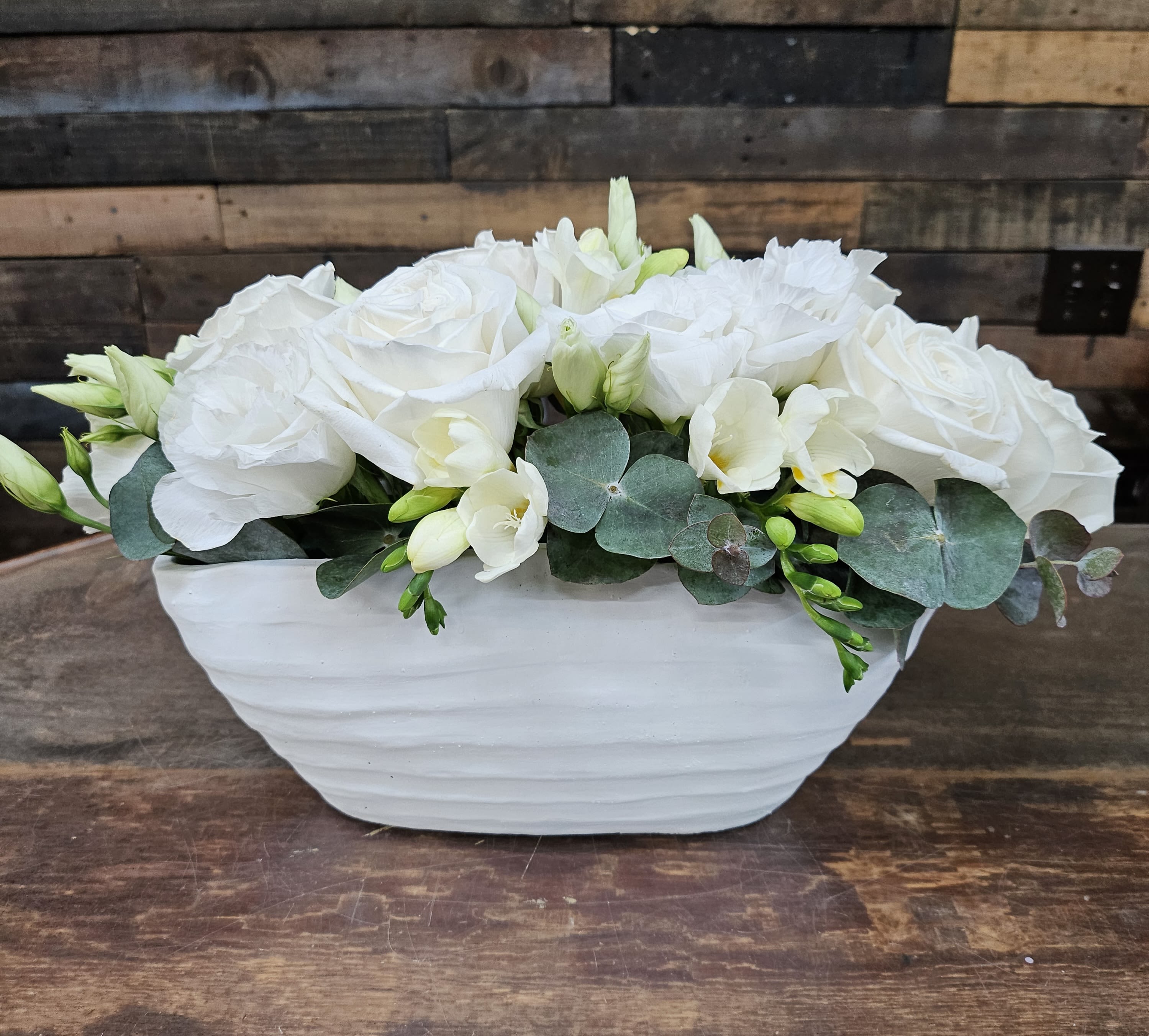 White roses and pale flowers in a white ceramic bowl