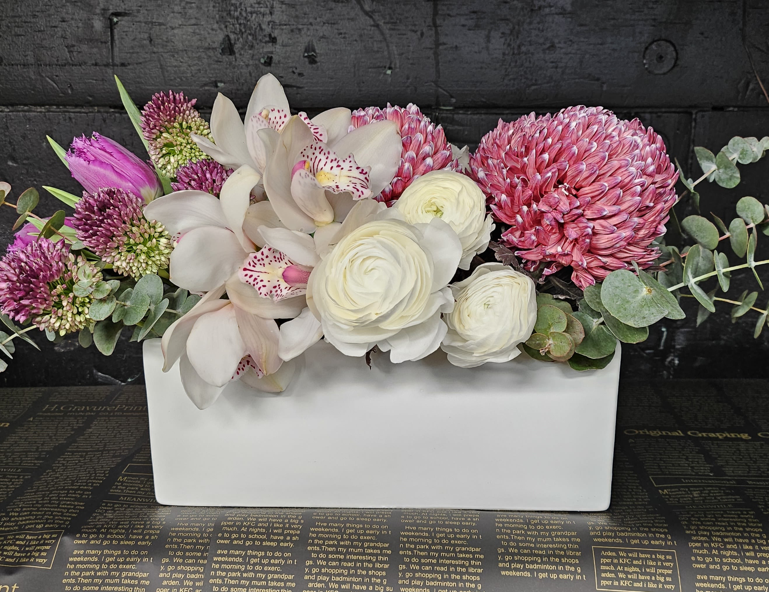 Pink and white floral arrangement in a white rectangular vase
